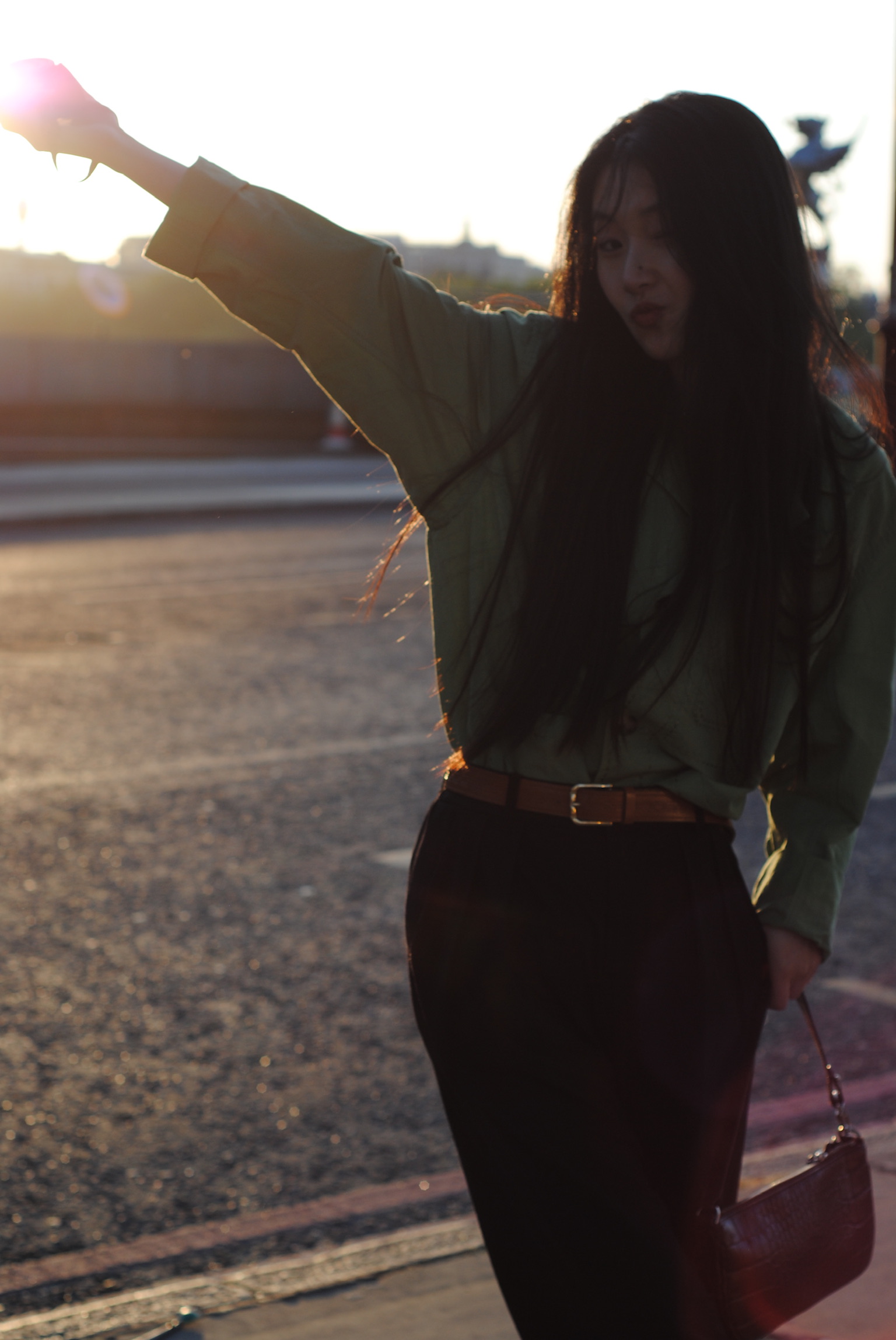 Young woman reaching toward golden hour light on street