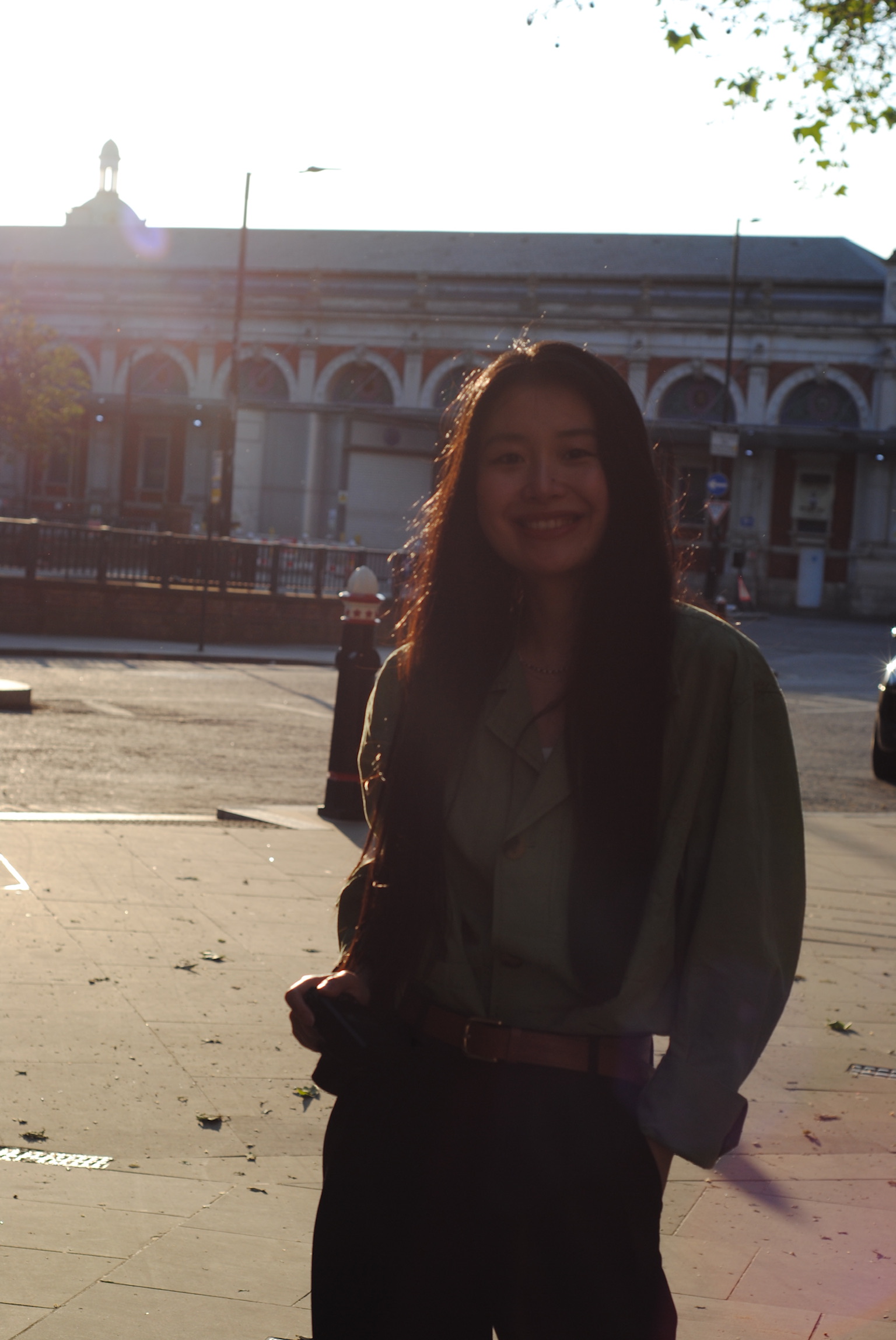 Young woman smiling in urban square with Victorian building